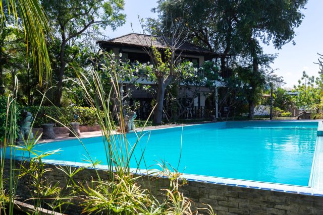 swimming pool blue water tropical garden with sea view background scaled e1759446723852